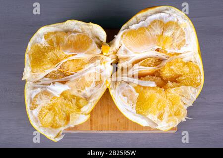 pomelo fruit top view, halves of exotic fruit on gray background. grapefruit hybrid. Stock Photo