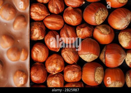Chocolate with hazelnuts, nuts in a shell in the form of a solid texture. Dessert-milk chocolate with nuts. Confectionery. Full screen top view Stock Photo