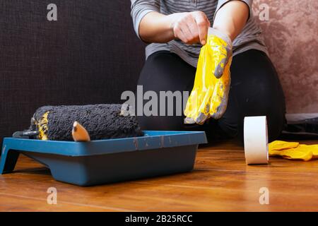 work painter puts on gloves. tools for home repairs, wall painting. Stock Photo
