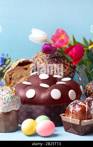 easter cakes and spring flowers, easter bread and eggs over blue background Stock Photo