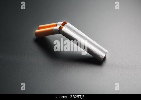 Two cigarettes in the form of a double-barreled shotgun on a black  background with copy space. Stop smoking. The concept of smoking kills.  Smoking as Stock Photo
