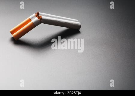 Two cigarettes in the form of a double-barreled shotgun on a black  background with copy space. Stop smoking. The concept of smoking kills.  Smoking as Stock Photo