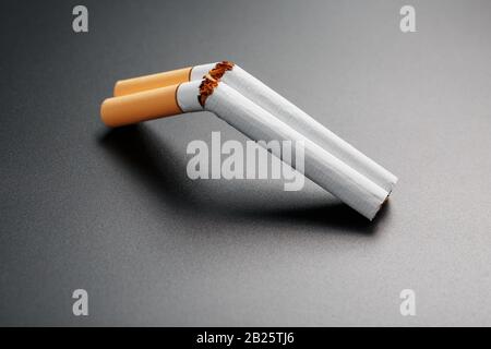 shotgunning cigarette smoke Two cigarettes in the form of a double-barreled shotgun on a black  background with copy space. Stop smoking. The concept of smoking kills.  Smoking as Stock Photo