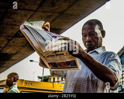 A man reads newspaper on a street in Lagos, Nigeria. Stock Photo