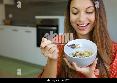 Close up of beautiful young woman eating skyr yougurt with cereal muesli fruit at home, focus on the model eyes, indoor picture. Healthy food concept. Stock Photo