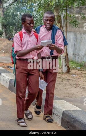Two students read a book while walking on the street in Lagos, Nigeria. Stock Photo