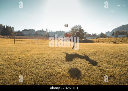 teen boy doing a bicycle kick in the evening sunlight Stock Photo