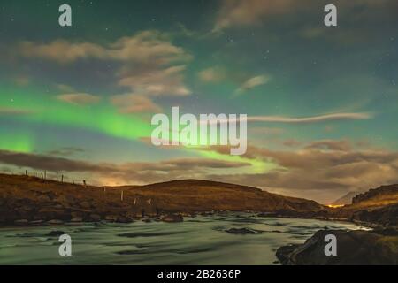 Aurora in Iceland northern lights bright beams rising in green beams reflecting in river Stock Photo
