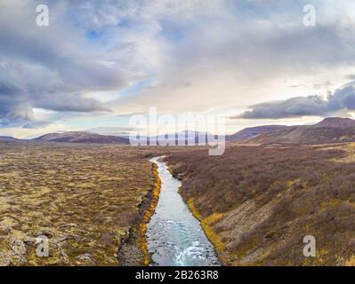 Hraunfossar series of waterfalls barnafoss aerial image of turquoise water next to lava field and the highlands Stock Photo