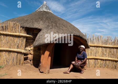 Basotho woman in front of traditional hut, Thaba Bosiu Cultural Village, Lesotho Stock Photo