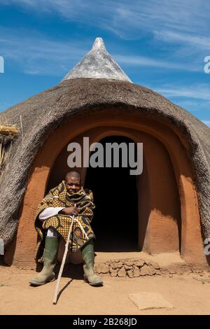 Basotho man in front of traditional hut, Thaba Bosiu Cultural Village, Lesotho Stock Photo