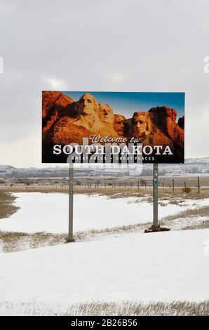 Road sign indicating entry into the state of South Dakota, United States of America. In the background grey sky and snowy meadow. Stock Photo