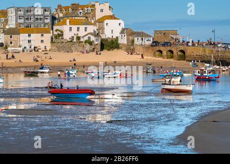 Views across St Ives Harbour beach to Smeatons Pier with people on the beach, boats in the Harbour and houses, St Ives, Cornwall, UK Stock Photo