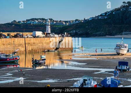 St Ives Harbour beach, with boats in the harbour with Smeatons Pier and St Ives new lighthouse, blue skies, blue sea, Cornwall, South West, UK Stock Photo