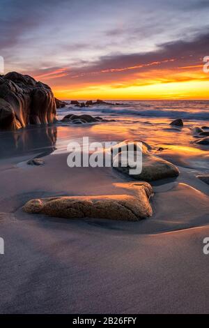 Dramatic sunset on the Cot Valley beach, Port Nanven, St Just, West Cornwall, romantic, dramatic skies, granite boulders, stunning, shoreline, horizon. Stock Photo