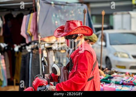 Man on a motorcycle wearing a red hat and red face mask. Stock Photo