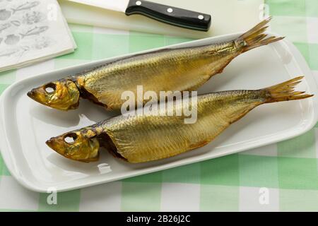 Pair of Buckling, hot smoked herring on a dish for a meal Stock Photo