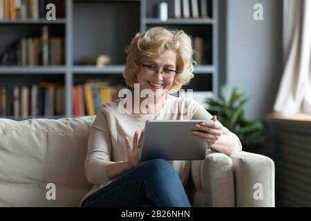 Middle-aged woman using tablet gadget at home Stock Photo