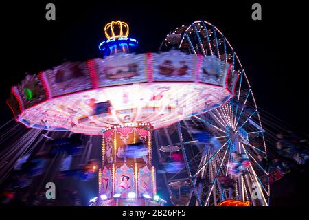 Motion blurred carousel by night with ferris-wheel in the background Stock Photo