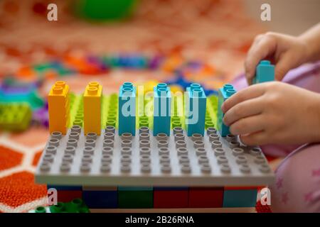 Multi-colored plastic constructor in the hands of the girl. Children's educational games. Close up Stock Photo