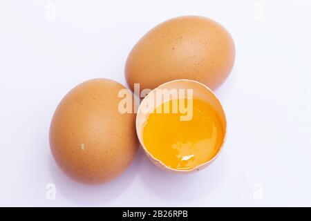 Three brown Eggs with one has broken isolated on white background Stock Photo
