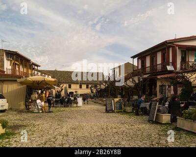 View down cobbled Demetri Liperti Street Omodos Cyprus with outdoor restaurants looking towards Monastery of Holy Cross in this attractive ancient mou Stock Photo