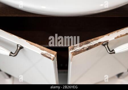 Water damaged high gloss white MDF bathroom vanity cabinet door with molding. Moist bathroom condition concept. Stock Photo