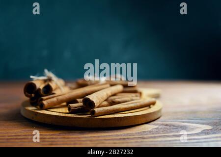 Cinnamon sticks. Wooden plate with cinnamon sticks and anise on table. Stock Photo