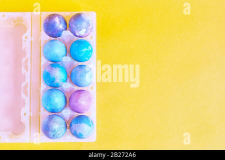Painted Easter eggs with space intergalactic pattern in stand on yellow background Stock Photo