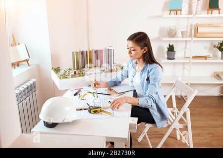 beautiful talented architect or engineer working on blueprint planning model building, using engineering tools at workplace , Construction and structu Stock Photo