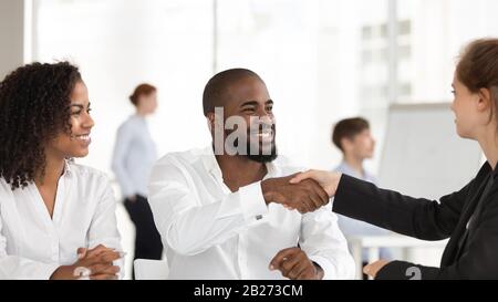 Smiling african american man handshaking female realtor at meeting negotiation Stock Photo