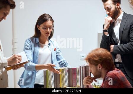 young awesome ambitious female designer in stylish shirt and glasses presenting the model of new building to colleagues.presentation, close up photo Stock Photo