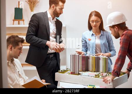 clever leader in glasses manages the process of construction, checking her colleagues' work, controlling her co-workers. team is creating a unique and Stock Photo