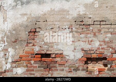 a beautiful old decaying concrete and red brick exterior wall exposed and falling apart Stock Photo