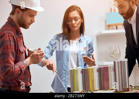 Confident leader of team of engineers showing the mistakes of the model, close up photo. detailed description of the new neighbourhood Stock Photo