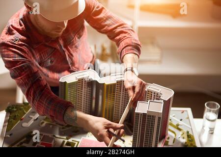 Architect in protective white helmet working with a ruler, examining model in the office, close up top view photo Stock Photo