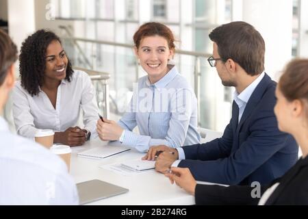 Young happy smiling woman talking to colleague in office. Stock Photo
