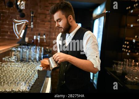 young stylish man in black vest and white shirt selling latte, close up side view photo Stock Photo
