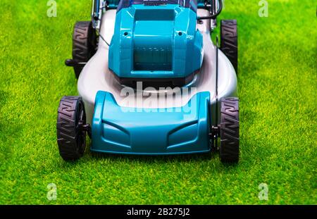 Turquoise lawn mower on grass. Stock Photo