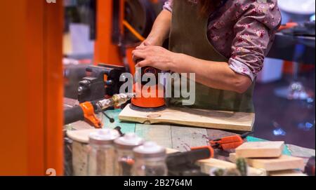 Worker grinds the wood of angular grinding machine. Stock Photo