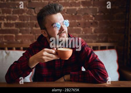 cheerful smiling man holding a cup of tea and looking aside, away, , good morning with perfect coffee, close up photo, guy dreaming about something, t Stock Photo