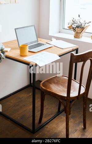 a reporter, journalist has left his laptop in the bedroom, close up side view photo.yellow cup, folder, paper, documents are on the table. working spa Stock Photo