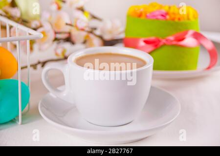 A cup of tea, small spring cake, flowers sakura, colorful eggs for Easter day. Spring concept Stock Photo