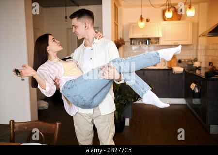 overjoyed family with keys to their new apartments, ready to move as soon as possible.close up photo. family dancing in the room, man carry his girlfr Stock Photo