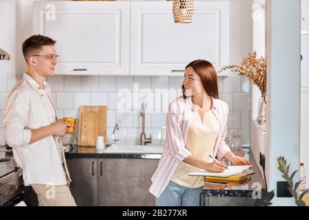 young good looking couple spending time in the kitchen with modern interior, family has conversation indoors. close up photo Stock Photo