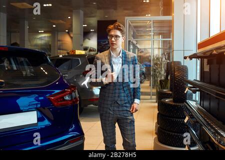 stylish young macho posing to the camera while waiting for customers, manager is working in the motor show. lose up photo, fashion, people Stock Photo