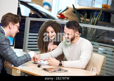 young guy in stylish suit explaining the options of contract to handsome man and his wife. close up side view photo Stock Photo