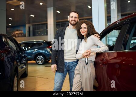 portrait of happy attractive couple showing the keys leaning near the car, close up photo. bargain, sale, discount, business. close up photo Stock Photo