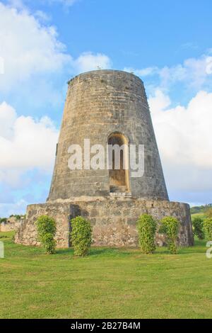 Awesome relic of a windmill on the grounds of Chateau Murat in Marie Galante with a bright blue cloudy sky in the backdrop Stock Photo