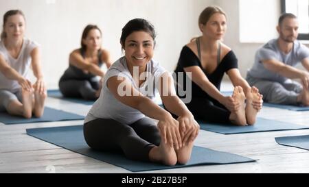 During yoga class group of people doing Seated Forward Bend Stock Photo
